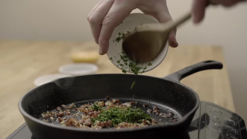 Person putting some spices on food in a pan then mixing it