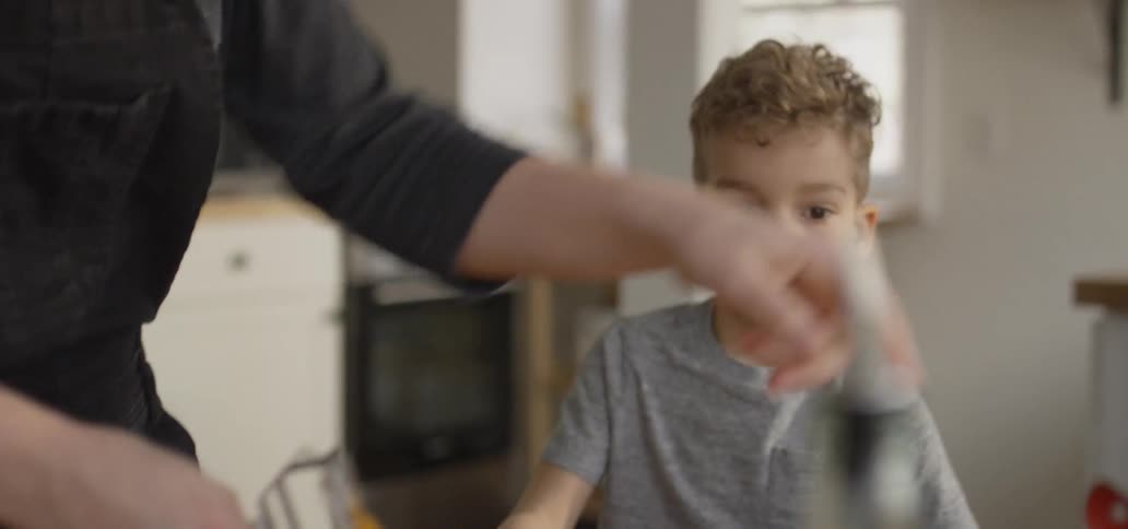 Woman peels carrots as a young boy watches