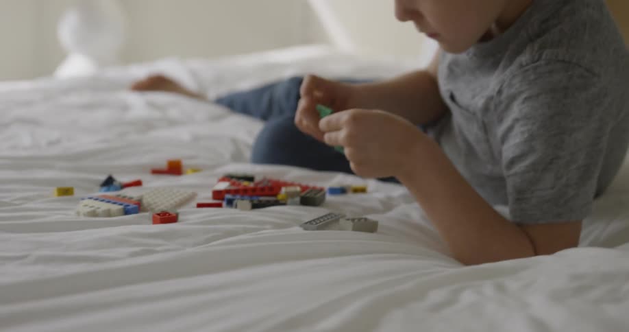 Boy plays with blocks on a bed