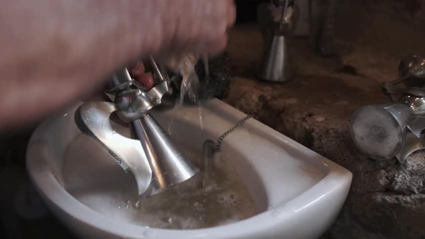 Man washes a metal statue in a small sink