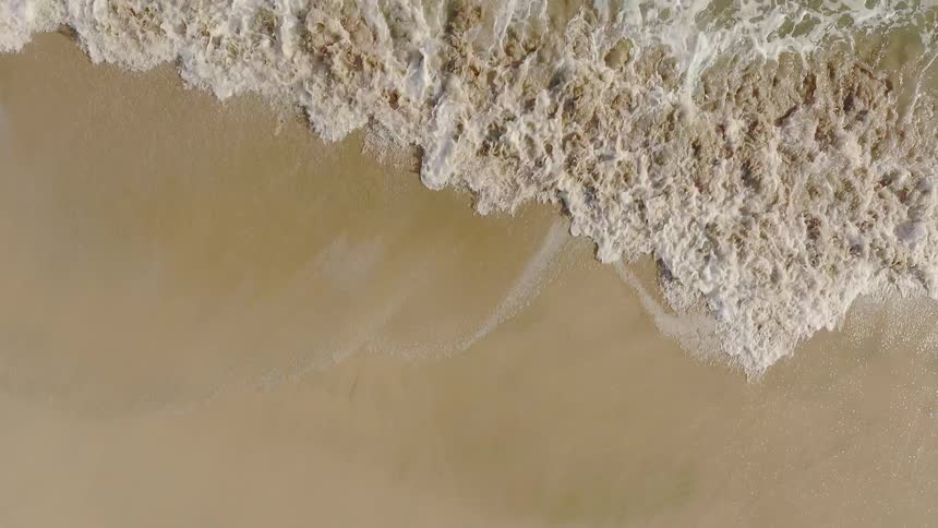 A wave is lapping the sand on a beach during the day