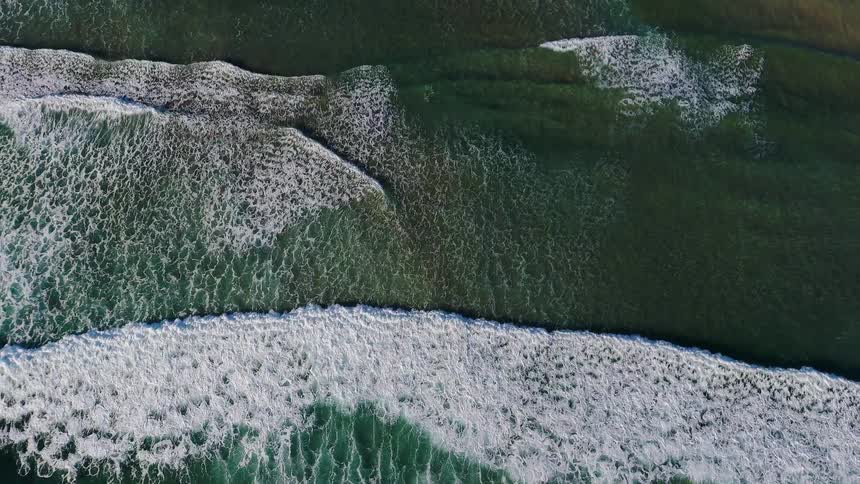 The waves slowly crash against the shore below