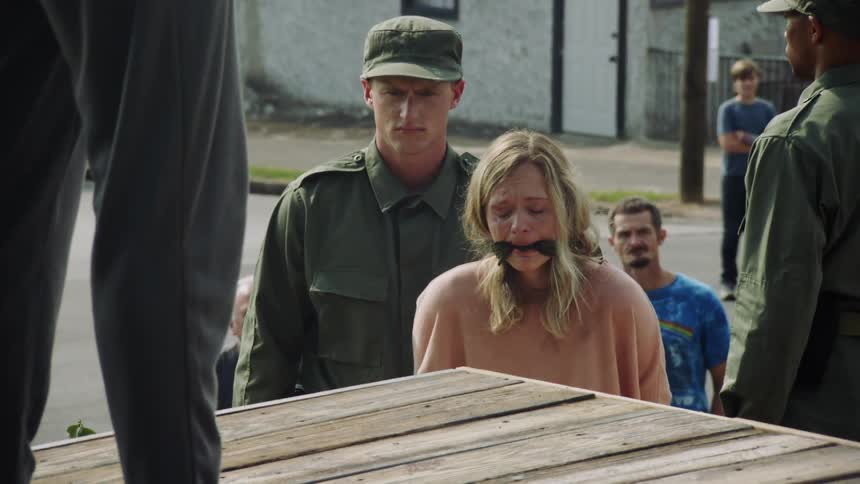 Soldier standing next to an upset women with a gag in her mouth