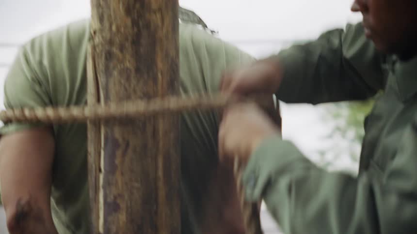 A man is tied to a stake with rope