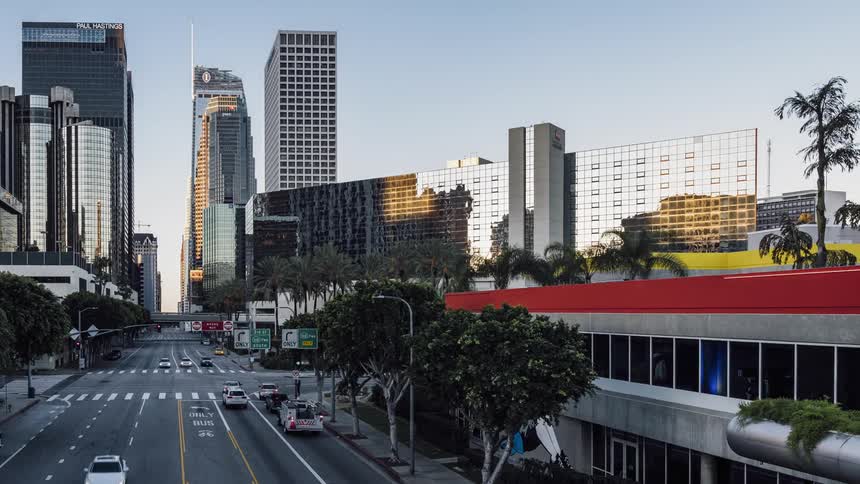 Traffic travels down a city street under a blue sky