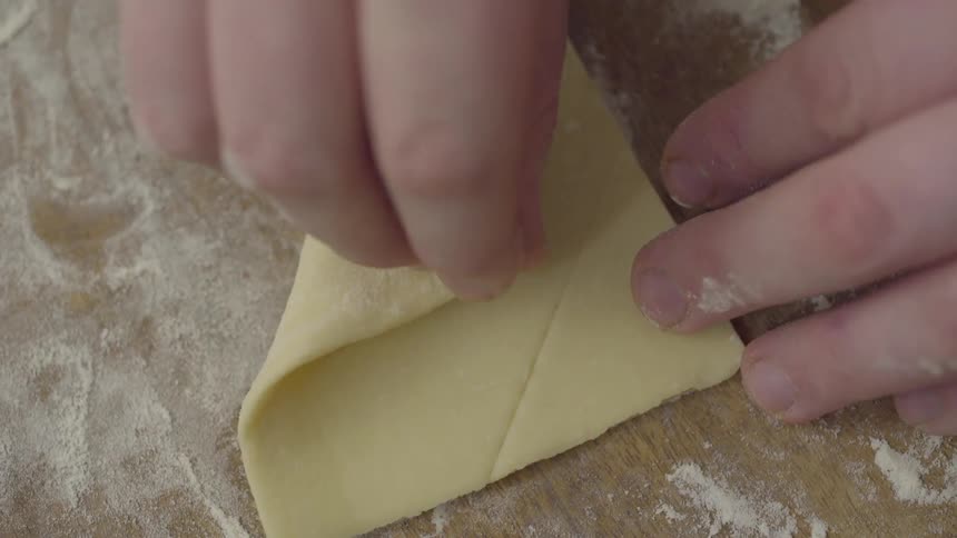 A person carefully folding a small square of dough