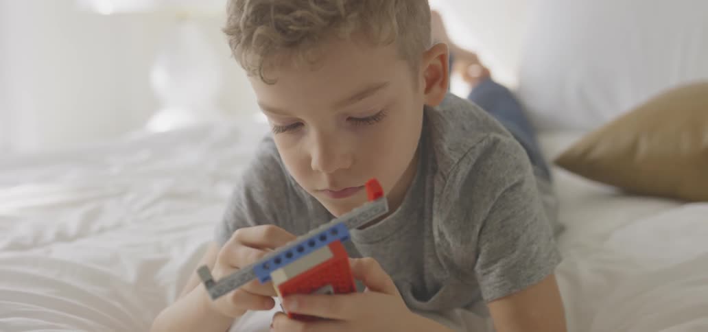 A boy plays with legos in bed