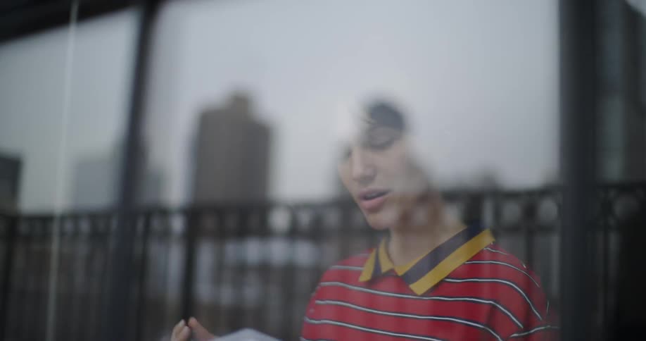 Woman studying something out loud while seeing out her window a large city