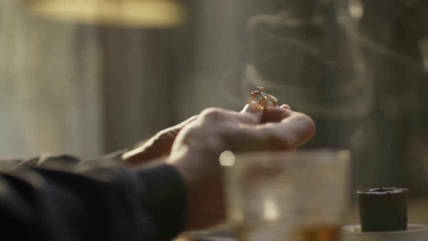 A man holds a ring near the smoke of a blown out candle