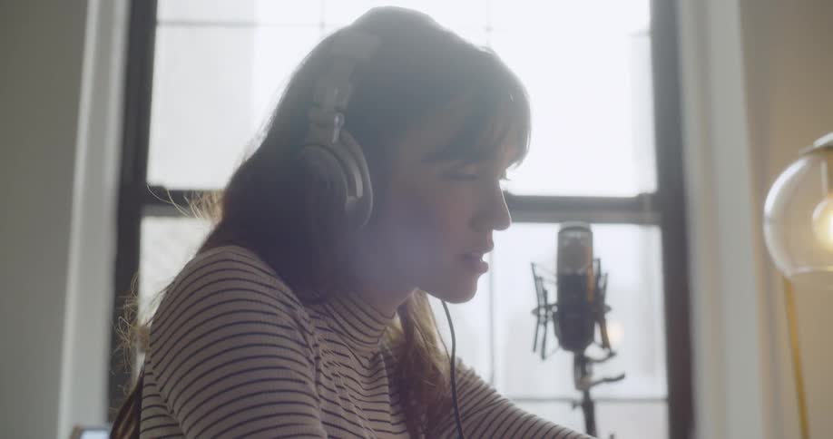 A woman works at the computer wearing headphones