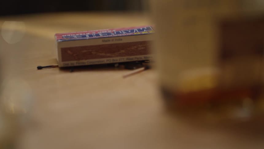 The table has matches, and a bottle of alcohol on it