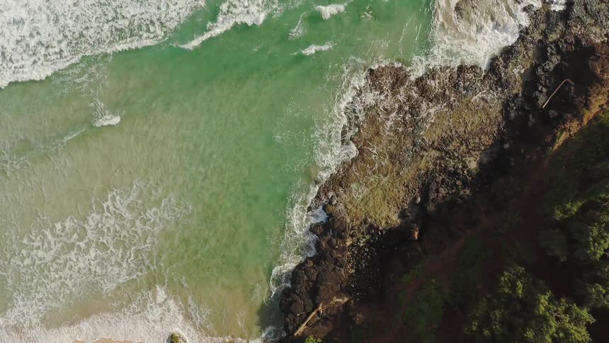 The tide flows towards the rocky shore