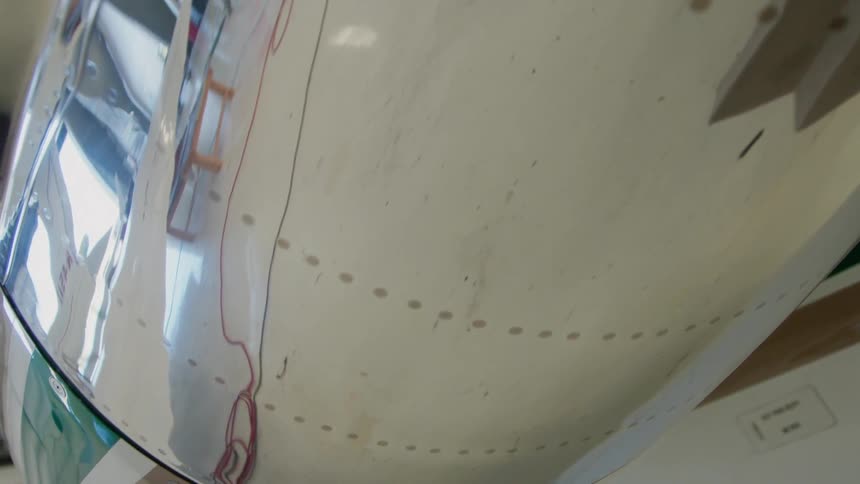 Shiny metal siding on airplane in hanger