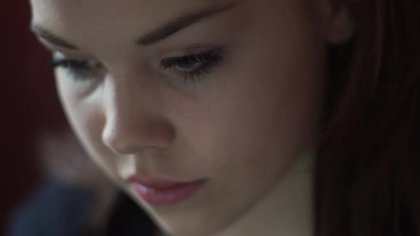 Girl looks down with lights flashing on her face