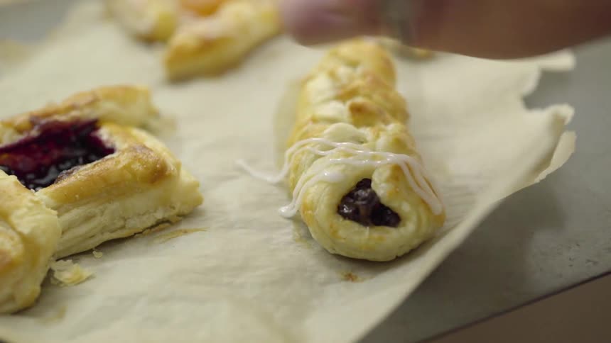 Someone is putting icing on a freshly baked pastry