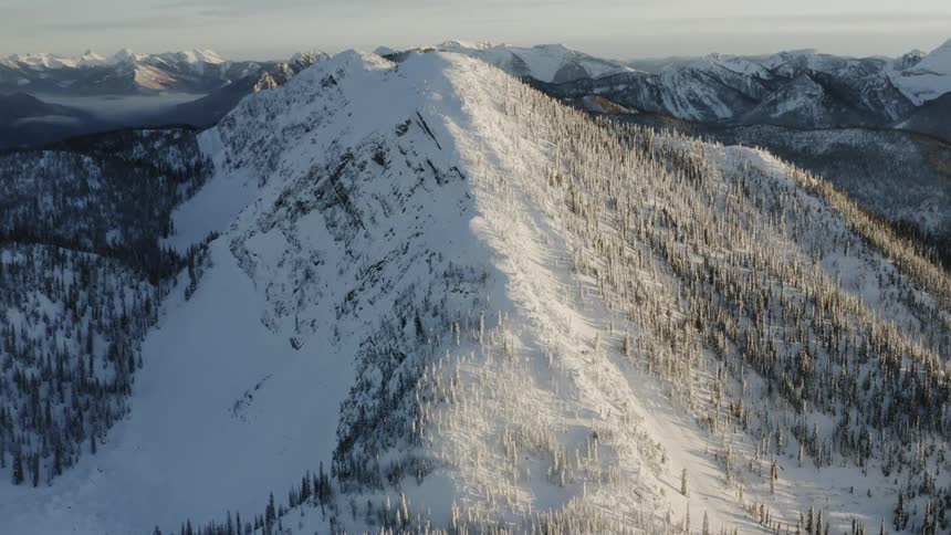 Sunlight is casting a glow on a mountain range in winter