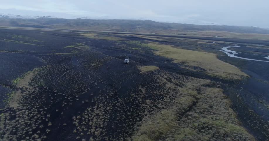 An suv travels over dirt and rock terrain near the water