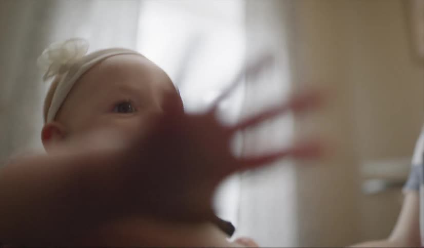 A woman is holding her baby in a standing position as they play inside in daylight