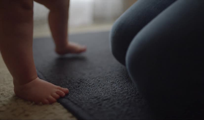 Woman kneels on a floor with a baby