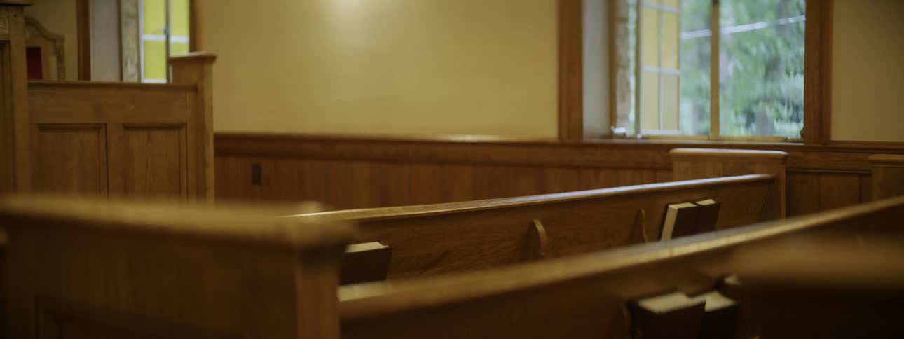 Church pews are sitting empty inside a church in daylight