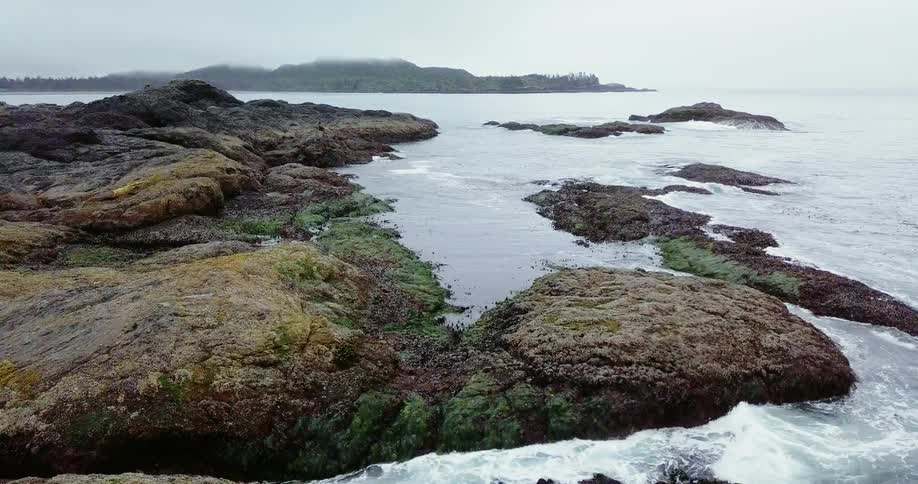 Water flows around rocky land under a blue sky
