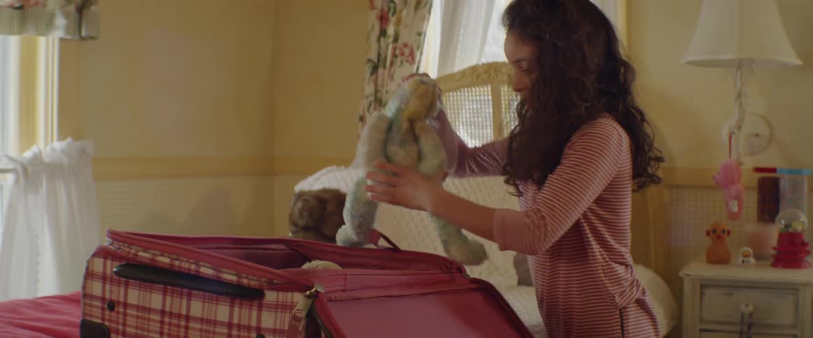Girl in bedroom packs suitcase