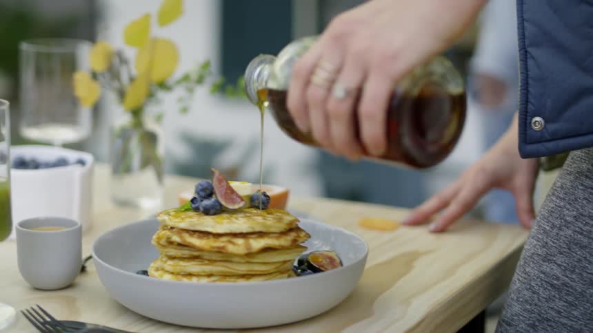 A person puts syrup on some pancakes