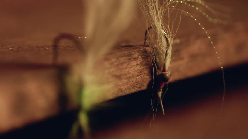 A fishing lure is hanging on a wood shelf