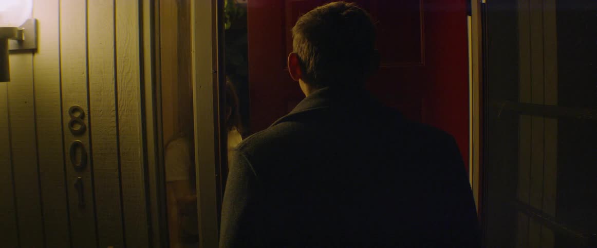 A man is knocking on a woman's door to surprise her at night