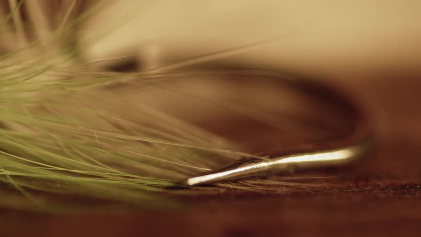 Green feathers with a piece of metal on a table