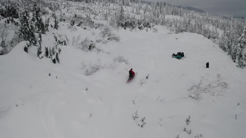 A person rides his snowmobile downhill