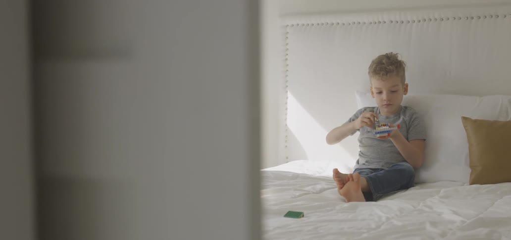 The child is playing with a toy in bed