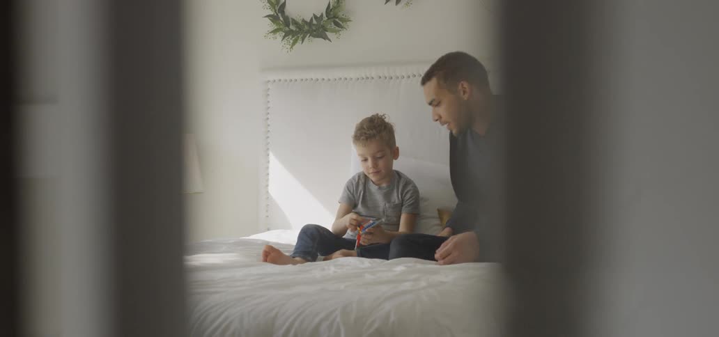 Man and child sitting on a bed