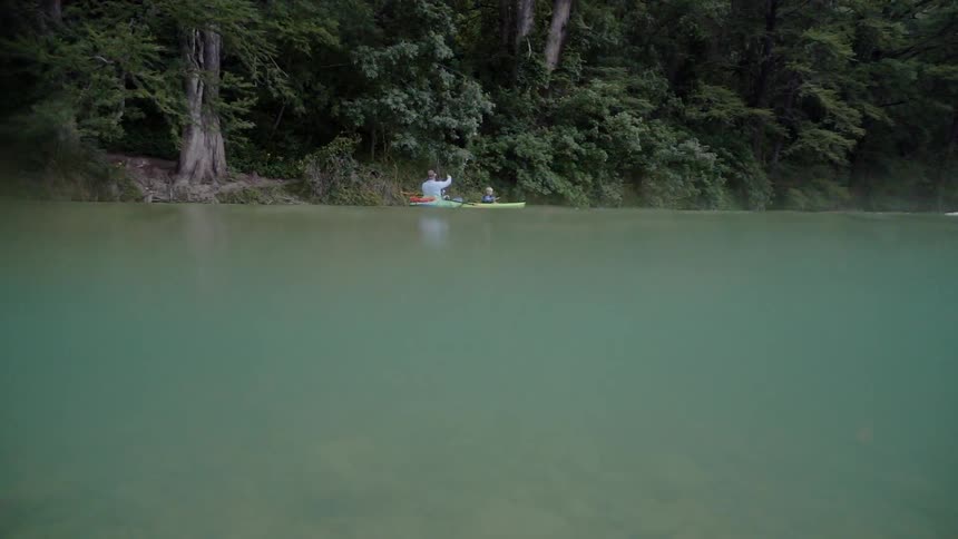 Canoes float on the water near a forest