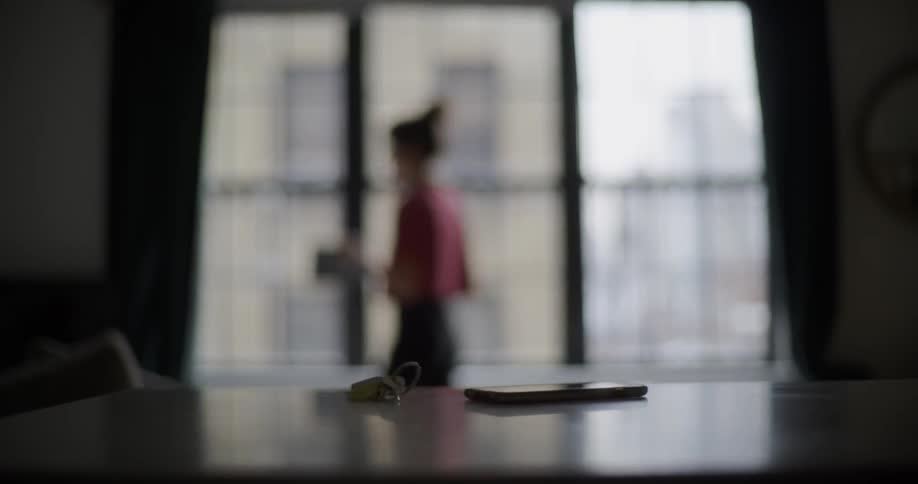 A woman paces in the room by the window