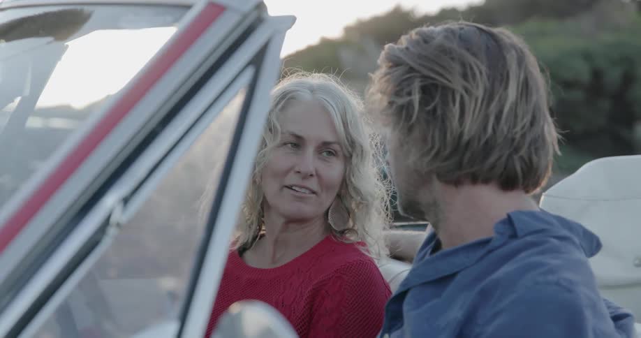 Woman and man talk as they sit in a convertible