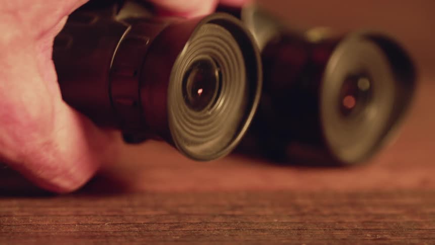 A pair of binoculars are being grabbed by a hand