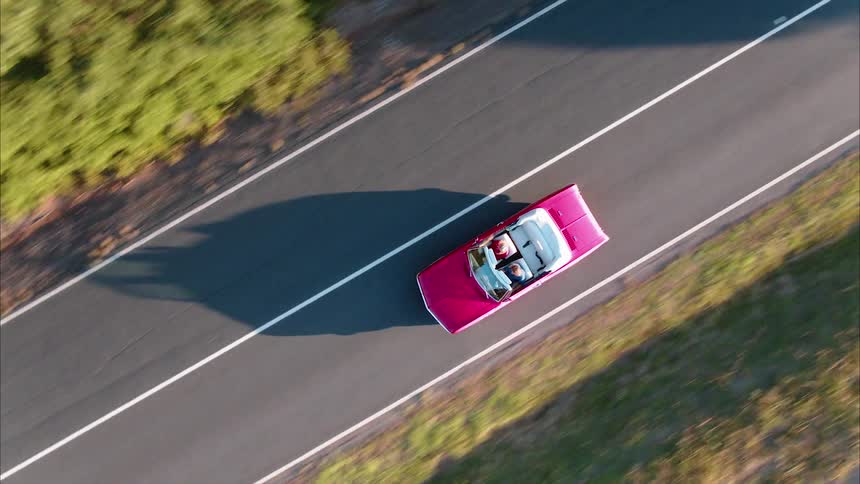 The red convertible speeds down the road