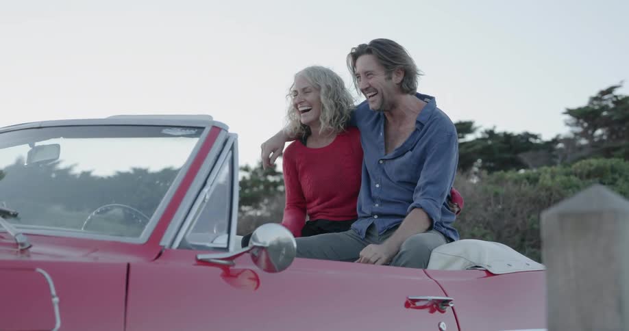 Man and woman sit in a parked convertible