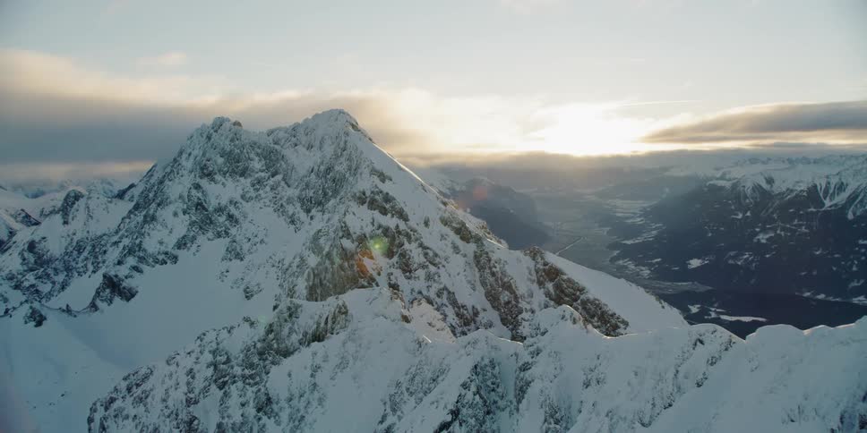 The sun is setting behind the mountains below