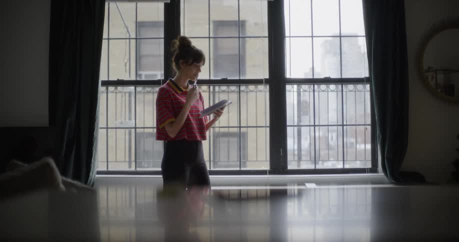 A woman walks around reading from a book