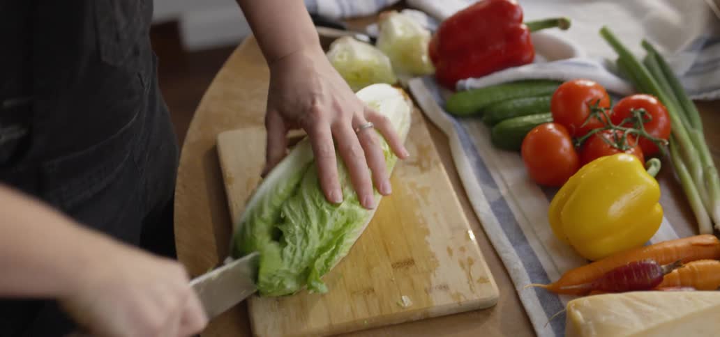 Person cuts a large wedge of lettuce on a cutting board