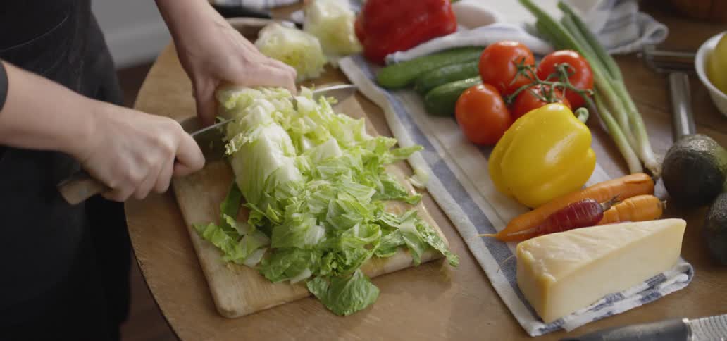 Man dices lettuce on a cutting board
