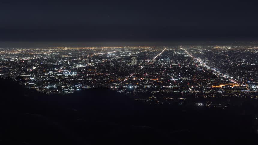 A hill overlooks the lights of a city at night