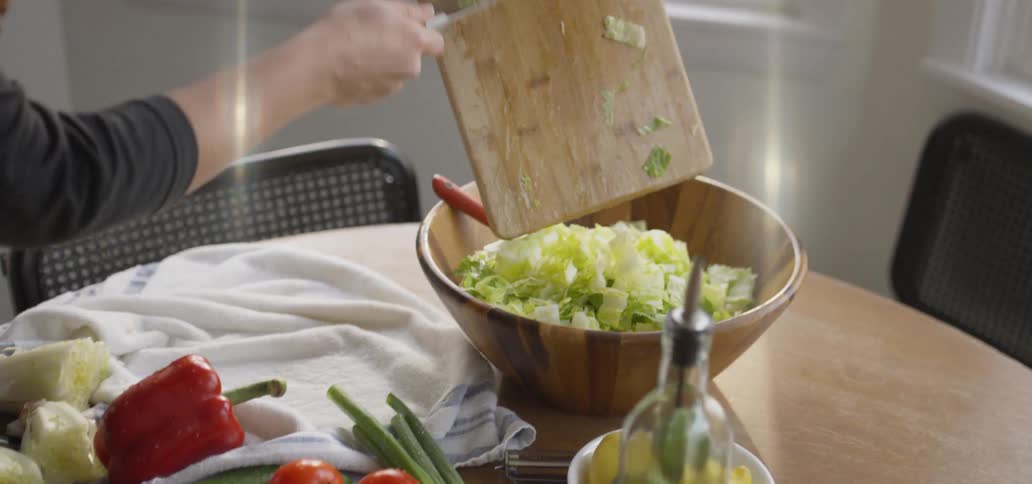 Cut lettuce is poured into a salad bowl