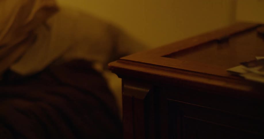 Woman reaches from her bed and grabs keys from the nightstand