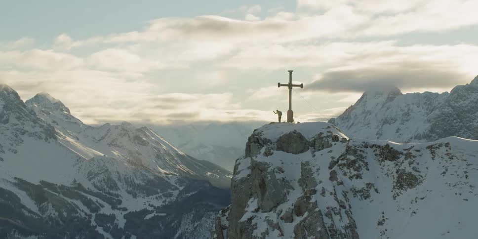 A large cross is on top of the mountain near a person
