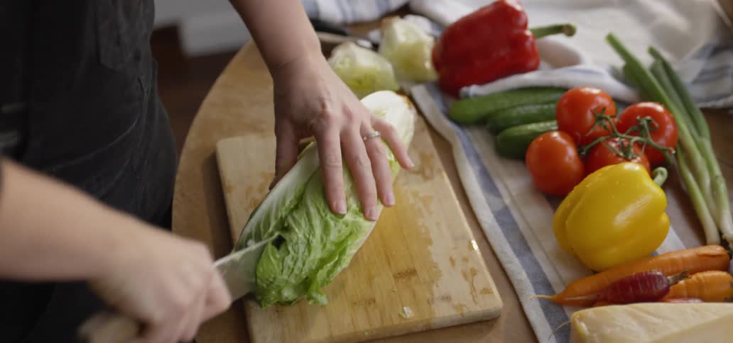 Man slices lettuce on a cutting board