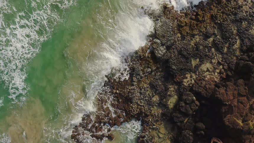 The waves flow towards the rocky shore