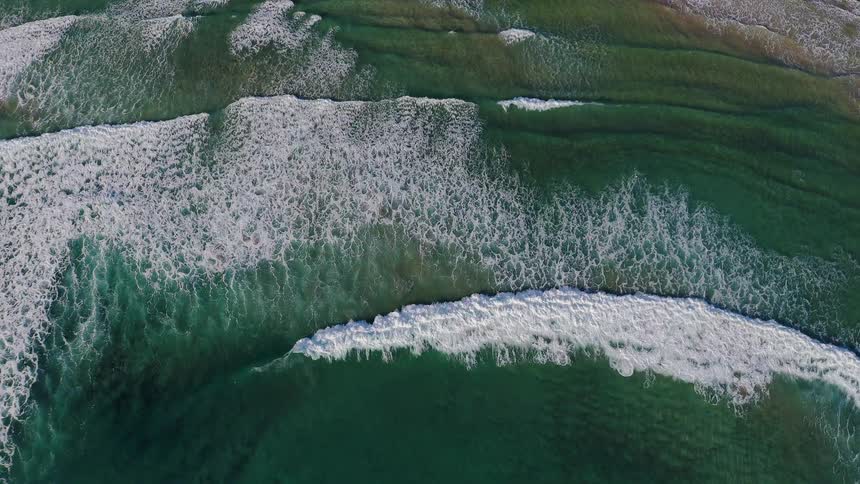 Waves are rolling onto a beach during the day